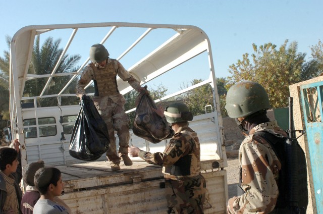 JERF AL MILA, Iraq - Iraqi Army soldiers from the 3rd Battalion, 2nd Brigade, 9th Iraqi Army Division (Mechanized) off load soccer balls from the back of their truck at an elementary school in Jerf Al Mila, in northwest Baghdad, Dec. 17 during an...