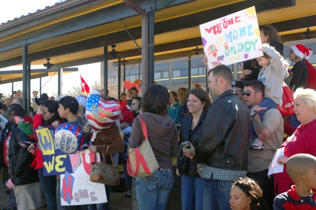 Hundreds of 1st Cavalry Division families stand with signs and balloons waiting for their Soldiers to come across Cooper Field at the 1st Cavalry Division headquarters Dec. 20. The Soldiers of the Division Special Troops Battalion and 1st Air Cavalry...