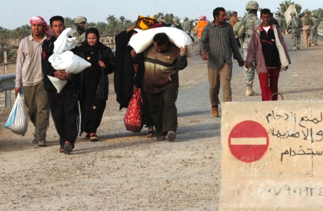 ABU OBAED, Iraq - After returning from buying goods at a nearby market, villagers on their way home pass by patrolling U.S. troops from Company A, 2nd Battalion, 5th Cavalry Regiment and the 2nd Battalion, 8th Cavalry Regiment on a bridge near...