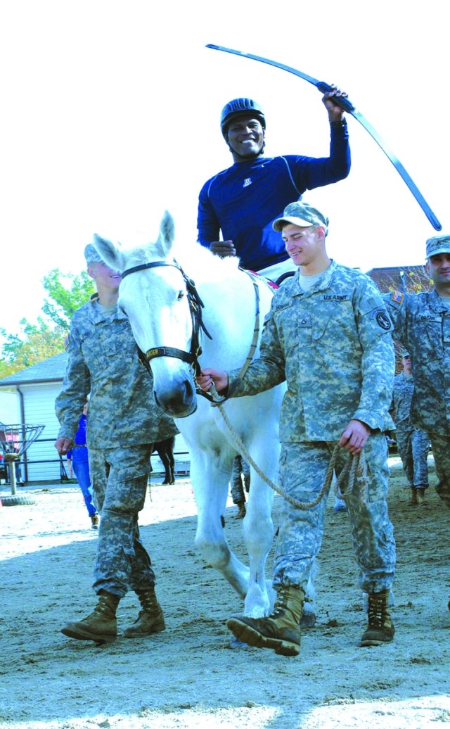 LTC Greg Gadson rides Ranger while volunteers from the Old Guard\'s caisson platoon guide the horse.