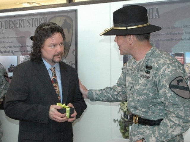 Maj. Gen. (P) Joseph F. Fil, Jr., 1st Cavalry Division's former commanding general (left), presents Jody Harmon with a gift after the unveiling his painting "The Surge" at the division's headquarters on Fort Hood, Texas, Feb. 1, prior to Fil...