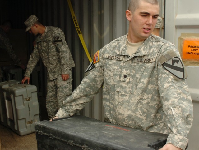 Spc. Marcus Hester, Headquarters and Headquarters Troop, 3rd Brigade Combat Team, 1st Cavalry Division, carries a fellow Soldier's tat box out of a shipping container he and his section are unpacking.  Cleaning out the unit containers is one step...