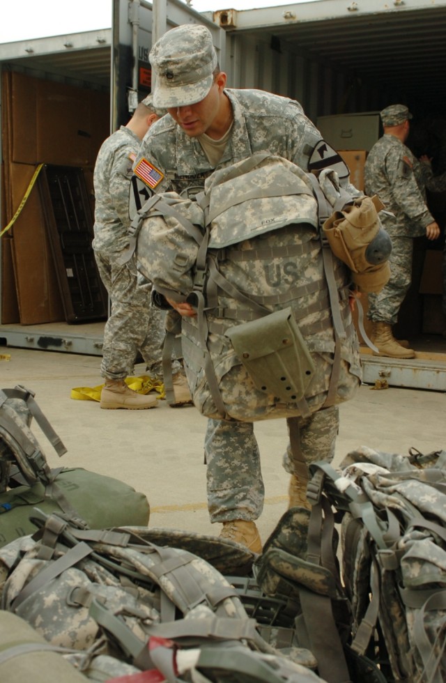 While helping his section unload their shipping container, Pfc. John Mendoza, Headquarters and Headquarters Troop, 3rd Brigade Combat Team, 1st Cavalry Division, carries a fellow Soldier's rucksack.  Mendoza, along with the rest of the Soldiers...