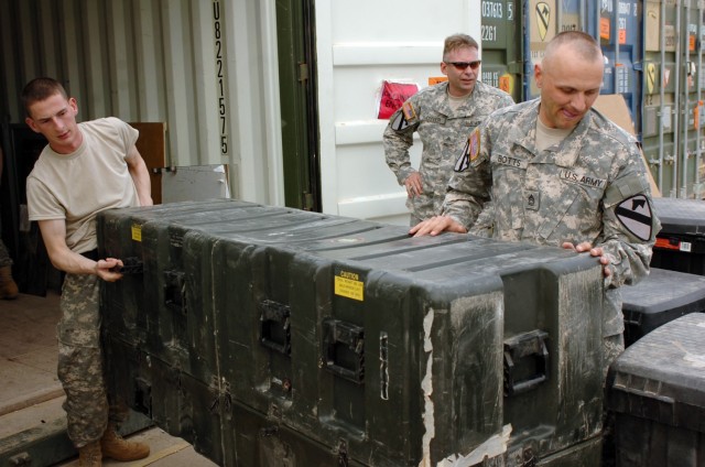Sgt. Matthew Stark and Sgt. 1st Class David Botts, both of Headquarters and Headquarters Troop, 3rd Brigade Combat Team, 1st Cavalry Division, unload a heavy container while unloading their unit's shipping containers.  Cleaning out containers is...