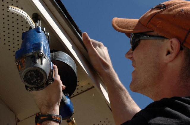 Sgt. Robert Zufall, of Company B, 1st Squadron, 12th Combined Arms Battalion, 3rd Brigade Combat Team, 1st Cavalry Division, nails paneling to the eave of a shed behind a house being worked on by Habitat for Humanity in the area around Fort Hood, Tex...