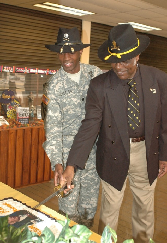 Retired Command Sgt. Maj. A.C. Cotton (right) cuts a ceremonial cake with a cavalry saber with Lt. Col. Barry Dickerson, the 1st Cavalry Division's Equal Opportunity Program manager at a Black History Month observance in the division's headquarters F...