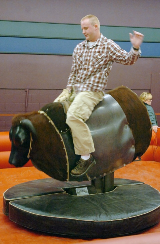 Spc. Dustin Morrissey, 15th Personal Service Battalion, attached to Headquarters and Headquarters Troop, 3rd Brigade Combat Team, 1st Cavalry Division, and a native of Springfield, Ill., rides a mechanical bull during the 3rd Brigade Special...