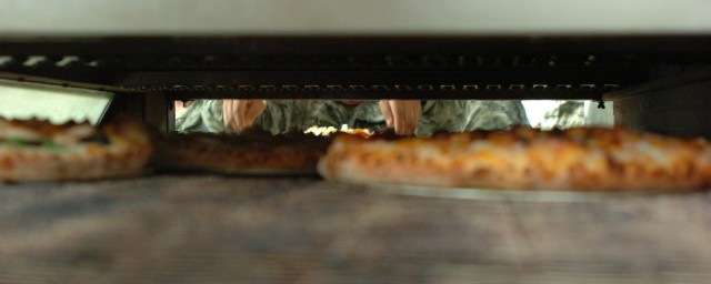 A Fort Hood Soldier places his self-made pizza into a rolling oven during a Soldier appreciation day hosted by the Copperas Cove's Domino's Pizza and organized by the city's Chamber of Commerce and Visitors Bureau March 10. According to the district ...