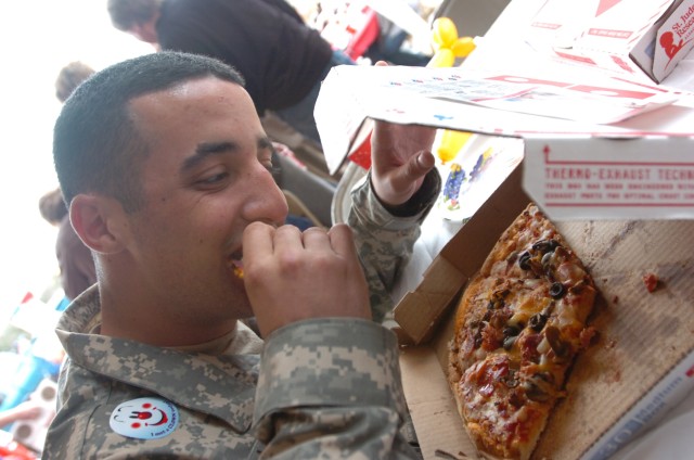 Rochester, N.Y., native Spc. Mark Mitchell, a signal support signal specialist with 1st Squadron, 7th Cavalry Regiment, 1st Brigade Combat Team, 1st Cavalry Division takes a bite of his pizza during a Soldiers appreciation day held at Domino's Pizza ...