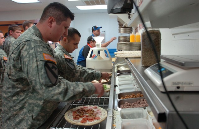 Infantryman Spc. Carlos Ramirez with 2nd Battalion, 5th Cavalry Regiment, 1st "Ironhorse" Brigade Combat Team, 1st Cavalry Division, travels down the line of possible topping before putting his finished pizza into the oven during a Soldier appreciati...