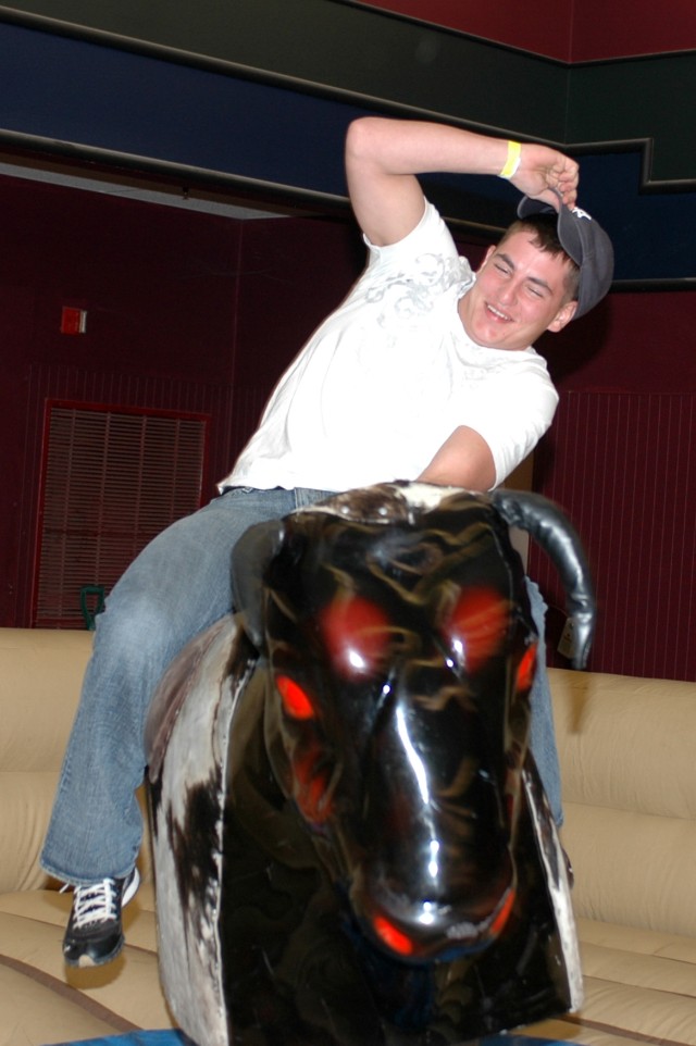 San Antonio, native Spc. Drew Alspach, a fueler for Company A, 615th Aviation Support Battalion "Cold Steel," 1st Air Cavalry Brigade, 1st Cavalry Division, tries to hold on to a mechanical bull during the Cold Steel welcome home and combat spur...