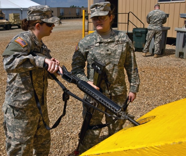 Spc. Cassandra Perry inspects fellow intelligence analyst Pfc. Karen Medlin's weapon at a clearing barrel before entering the Forward Operating Base Sword dining facility for lunch March 14. The clearing barrels at the Joint Readiness Training...