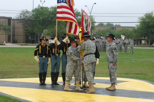 Brig. Gen. (P)Vincent Brooks, 1st Cavalry Division commander, center, passes the 1st Air Cavalry "Warrior" Brigade guidon to it's incoming commander, Col. Douglas M. Gabram, left, as the outgoing commander, Col. Dan Shanahan, right, looks on,...