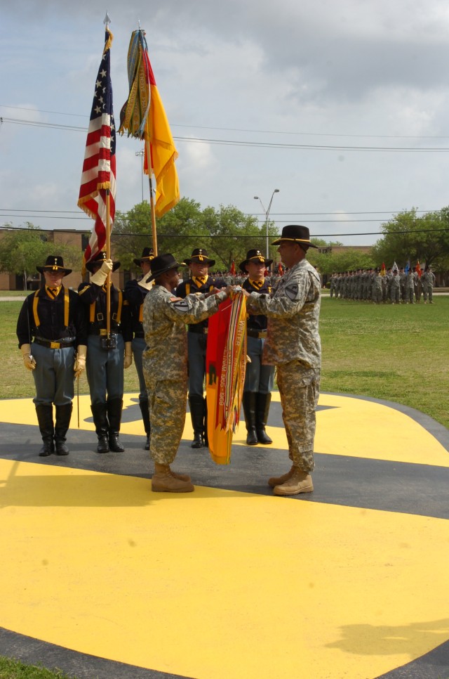 Col. Bryan Roberts (left), the outgoing commander of the 2nd Brigade Combat Team, 1st Cavalry Division, and Command Sgt. Maj. James Lee, the brigade's top noncommissioned officer, attach the Operation Iraqi Freedom Campaign streamer to the colors...