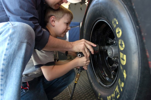 Capt. Lexie Gibbs, commander Headquarters and Headquarters Company, 2nd Brigade Combat Team, 1st Cavalry Division, helps his son Alex tighten some lug nuts  for fun during the "Salute to our Soldiers" day at the Fort Hood stadium April 11....