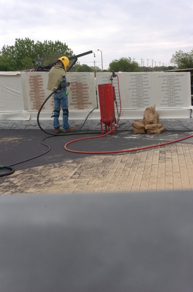 Wayne Smith with the Waco, Texas-based monument business Phipps Memorial, sands down the names of fallen heroes at the Operation Iraqi Freedom memorial beside Fort Hood, Texas's Cooper Field April 16. The 1st Cavalry Division's memorial is scheduled ...