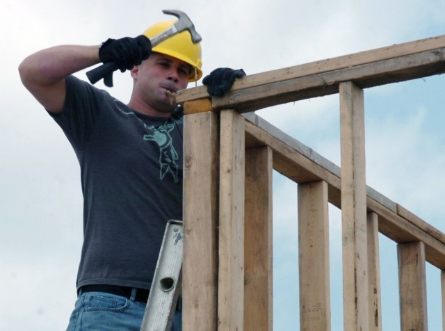 Austin native Spc. James Smith, an engineer with Company E, 2nd "Stallion" Battalion, 8th Cavalry Regiment, hammers nails into a frame May 1 which makes up part of a new shed that will store equipment for the Habitat for Humanity organization in Kill...