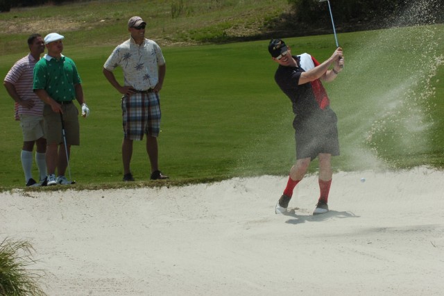 Capt. Mark Hill, assigned to 3rd Battalion, 82nd Field Artillery, 2nd Brigade Combat Team, 1st Cavalry Division, tries to hit his way out of a sand trap while the rest of his team looks on during the Black Jack Golf Scramble, which was held at the...