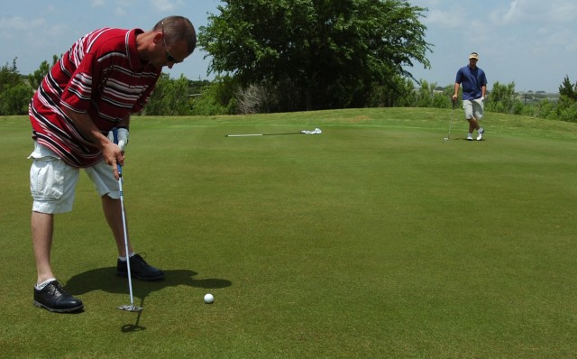 Sgt. Curtis Young, assigned to 15th Brigade Support Battalion, 2nd Brigade Combat Team, 1st Cavalry Division gets ready to putt, while Spc. Morgan McGough, also with 15th BSB, looks on. Young and Curtis were taking part in the Black Jack Golf...