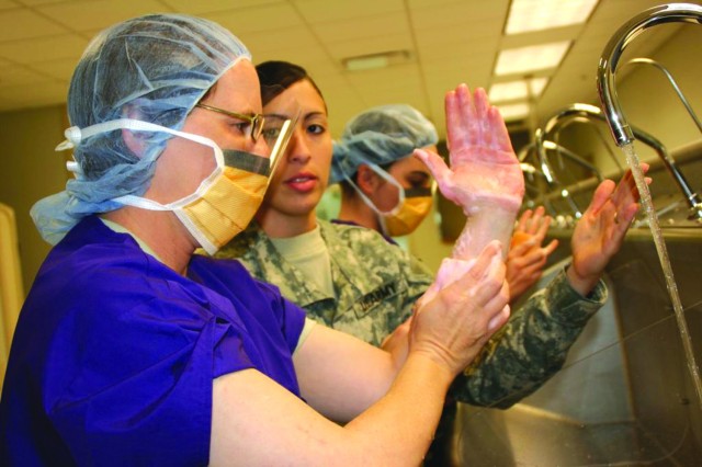 Instructor Staff Sgt. Zulaika DeLeon teaches Pvt. Darcy Quimby how to scrub-in for surgery using the scrub sinks at Dunlap Hall of the AMEDD Center and School.