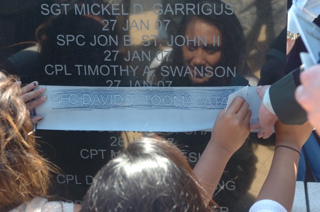 Doreen Toomalatai (center), sister of fallen Soldier Pfc. David Toomalatai, a medic with the 1st Cavalry Division, rubs a marking of her brother's name with the help of her sister, Shavi (left), after a memorial rededication ceremony held at the divi...