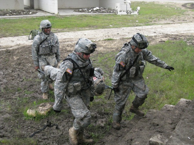Spc. Andrew Chung (right), of Hillborough, Calif., and Pfc.s Antonio Champion (rear) of Tennmark, S.C. and James Fender, of Phoenix, Ariz. perform a three-man, litter carry from the casualty collection point to the Aid Station during a mass...