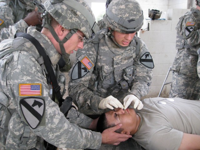 Spc. Blake Tenimon, from Longview, Texas, (left) provides head and neck stabilization as Pfc. Paul Osborne, of Melbourne, Fla., inserts a nasopharyngeal tube into a 1-7 Cav. Soldier's nose during a mass casualty event. Dark Horse Medics trained...