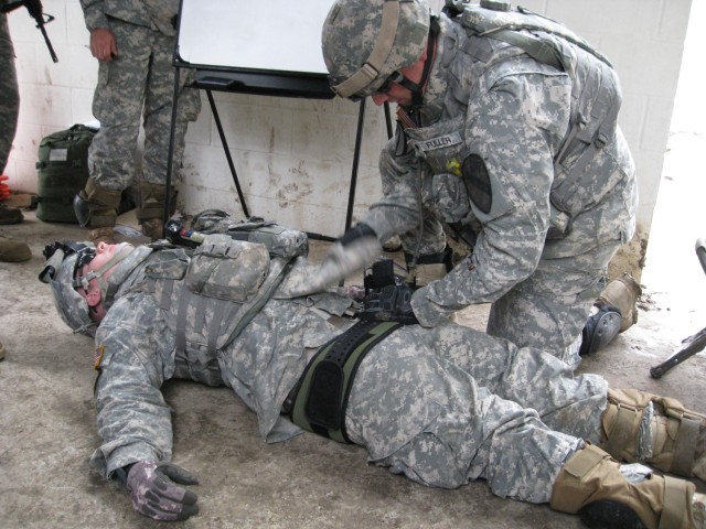 Spc. Mark Fuller (right) of Waterbury, Conn., provides care to a fellow Soldier by applying a brace to a notional broken pelvis. Dark Horse Medics trained on Evaluation and Treatment of a Casualty during platoon training exercise at the Elijah...