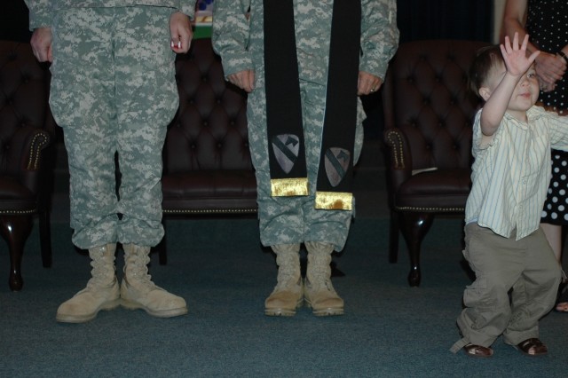 Chaplain (Lt. Col.) Steve Walsh (center), the 1st Cavalry Division's outgoing chaplain, stands ready to pass the stole and responsibility to the divisions new chaplain, as his 3-year-old son Joseph joins him on the stage, during a changing of the...