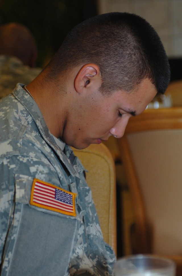 Merced, Calif. native Pvt. David Byrd, chaplain's assistant for 1st Battalion, 82nd Field Artillery Regiment bows his head in reverence touched by the special song during the 1st "Ironhorse" Brigade Combat Team, 1st Cavalry Division prayer luncheon J...