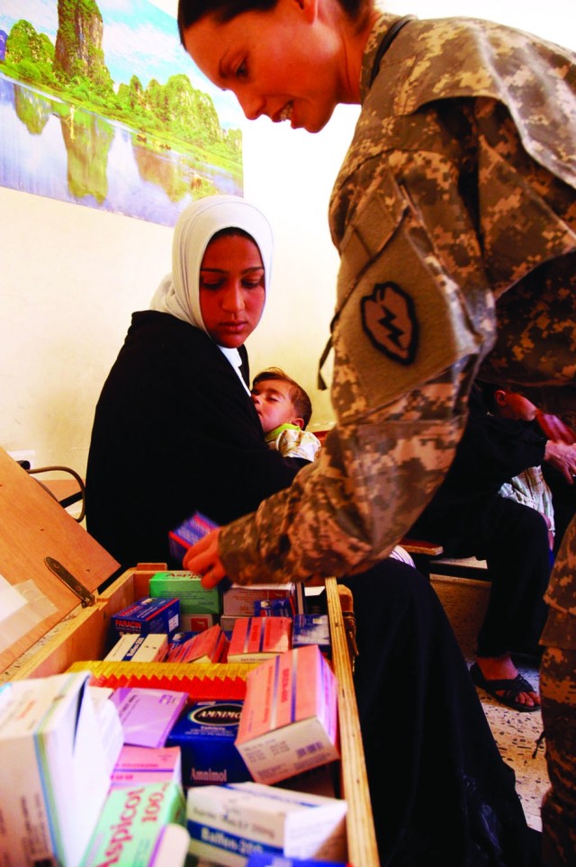 Capt. Jody Brown looks for medication for a patient during a combined medical effort in Batta village in Iraq.