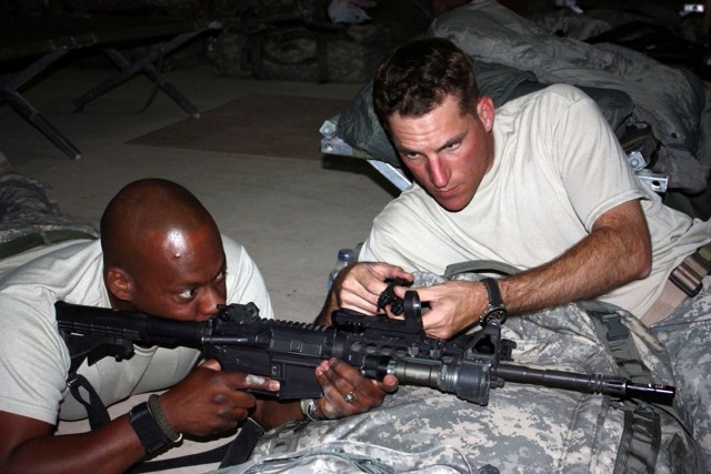 The 4th Brigade Combat Team, 1st Cavalry Division's Sgt. 1st Class David Groce, non-commissioned officer in charge of the Special Weapons Exploitation Team, who hails from Fort Drum, N.Y., assists Staff Sgt. Robert Cline, also of the 4th BCT,  by adj...