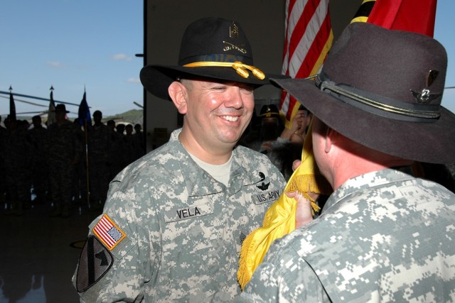 Dallas native Command Sgt. Maj. Glen Vela (left), the incoming command sergeant major for the 1st Air Cavalry "Warrior" Brigade, 1st Cavalry Division, accepts the brigade guidon from Cleveland native Col. Douglas Gabram (right), commander of the Warr...