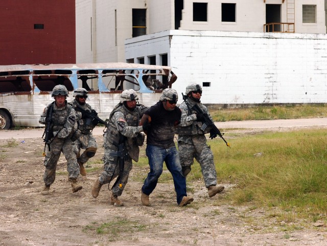 Cavalry scouts from Troop B, 4th Squadron, 9th Cavalry Regiment, 2nd Brigade Combat Team, 1st Cavalry Division, evacuate from a building with a simulated insurgent cell leader in custody during an air assault training operation dubbed "Operation Dark...