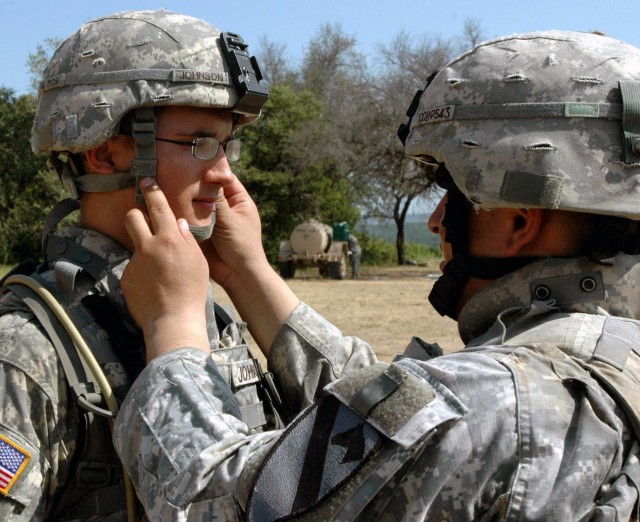 Pfc. Kyle Johnson, a tank crewmember with Company C, 3rd Battalion, 8th Cavalry Regiment, 3rd Brigade Combat Team, 1st Cavalry Division from Waterloo, Iowa has his chin strap adjusted by Staff Sgt. Kevin Barrantes, from Queens, N.Y., a tank...