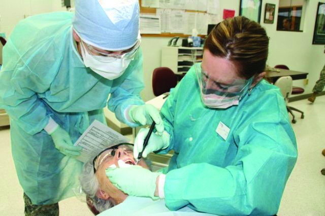 Instructor Darlene Furlow reviews an intra-oral examination performed by student Sgt. Amber McGraw on patient Lois Fugit. Instructors perform four mandatory checks on each patient