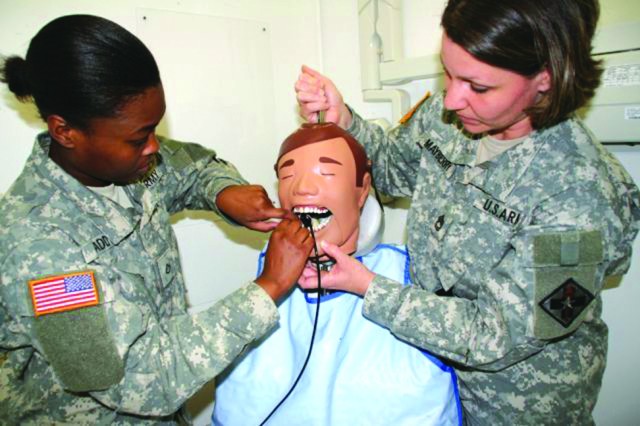 Pvt. Jasmine Gaddy (left) positions a sensor so she can take a digital X-ray while instructor Sgt. 1st Class Heidi Mayberry helps by holding open the mouth of the mannequin used as