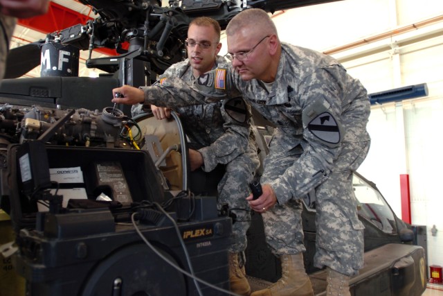 Buffalo, N.Y., native Sgt. Brett Bolt (left), an aircraft power plant mechanic for Company D, 1st "Attack" Battalion, 227th Aviation Regiment, 1st Air Cavalry Brigade, explains how to inspect the engine blades of an AH-64D Apache attack helicopter...