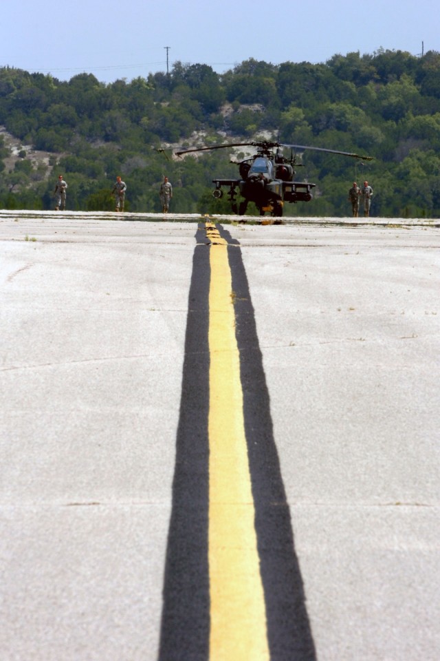 Crew chiefs from 1st "Attack" Battalion, 227th Aviation Regiment, 1st Air Cavalry Brigade, 1st Cavalry Division, slowly move through the heat as they guide an AH-64D Apache attack helicopter to the hangar for repairs at Robert Gray Army Air Field,...