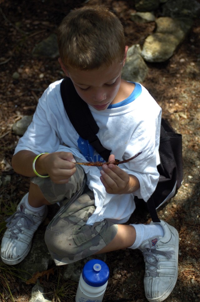 A young participant in the Armed Services YMCA summer camp examines a feather he found during a nature hike. Campers enjoy numerous trips to the nature trail during their camp experience, where their nature guide finds new and interesting things...
