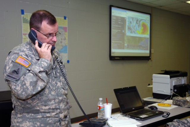 While Hurricane Ike looms on the screen in the background, Chief Warrant Officer 5 Dan Wallace, a liaison officer for 1st Air Cavalry Brigade, 1st Cavalry Division, works details of a mission at the Air Coordination Group, Camp Mabry, Texas, Sept....