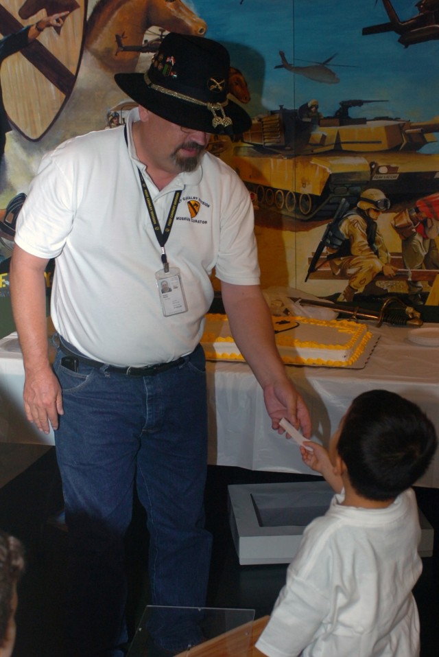 During a drawing in which a Soldier could win a new Stetson, Sean Layton (right), a little boy visiting the 1st Cavalry Division Museum, picks the "winning" name out of a box and hands it to Steven Draper, the museum director, during the 1st Cav....