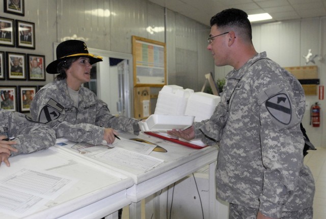 Specialist Rose Picard, a food service specialist assigned to the Headquarters and Headquarters Company, 27th BSB, 4th BCT, 1st Cav. Div., hands a plate to Spc. Thaddeus Dmuchowski.  Both Soldiers were at the COB Adder dining facility to celebrate...