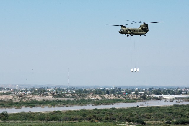 A CH-47F Chinook helicopter from the Company B "Black Cats," 2nd Battalion, 227th Aviation Regiment, 1st Air Cavalry Brigade, 1st Cavalry Division, sling loads three oversized sandbags on their way to a levee in Presidio, Texas, near the Rio Grande R...