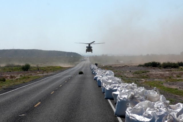 A CH-47F Chinook helicopter from the Company B "Black Cats," 2nd Battalion, 227th Aviation Regiment, 1st Air Cavalry Brigade, 1st Cavalry Division, approaches a road in Presidio, Texas, to pick up sand bags Sept. 22. The Black Cats are currently supp...