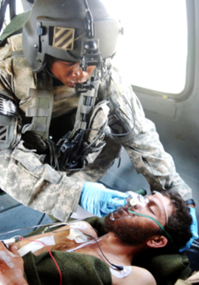 Staff Sgt. Atwon Thompkins of 6th Battalion, 101st Aviation Regiment, puts oxygen mask on an Afghan during helicopter transport.