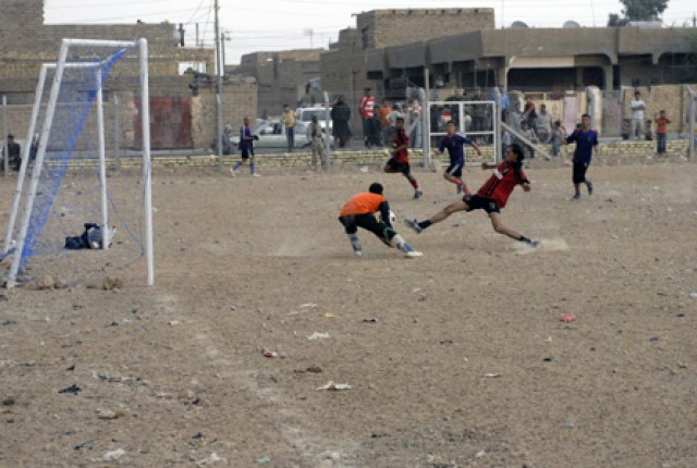 A member of the Iraqi Army team kicks the ball pass the goalie of the Abu Rummanah District All-stars on the new soccer field in Amarah, Iraq, Oct. 23. The 4th Brigade Combat Team, 1st Cavalry Division Soldiers, attended the soccer game supporting...