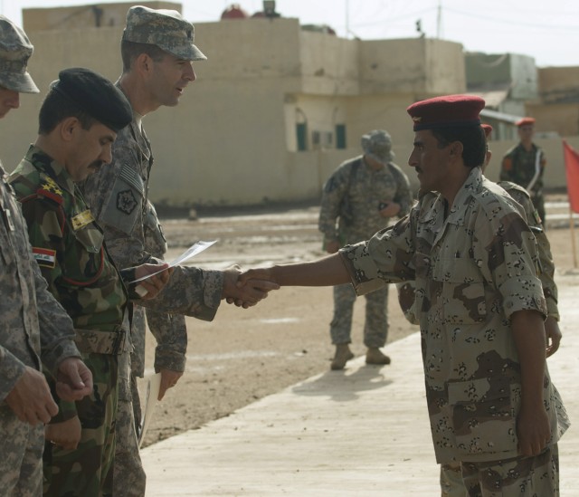 Iraqi Pvt. Hazim Karim, the honor graduate and "best Sapper" of the 10th IA Division's first Route Clearance Academy class, shakes hands with Lt. Col. Peter Helmlinger, commander of the 14th Eng. Bn., from Fort Lewis, Wash., during the class' graduat...