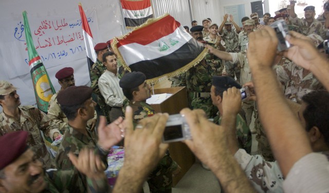 Newly commissioned Iraqi Army officers cheer 'Iraq! Iraq! Iraq!' as Brig. Gen. Arif, the RTC commander at Camp Ur holds up the national flag during the training center's first officer course graduation ceremony Oct. 15. The training center...