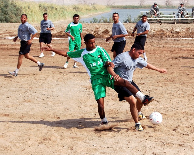 Sgt. Freddy Valdez, assigned to the 27th BSB, 4th BCT, 1st Cav. Div., attempts to reach a soccer ball before an Iraqi MTR Soldier with the 10th IA Div., can kick the ball away during a soccer match at Contingency Operations Base Adder in southern...
